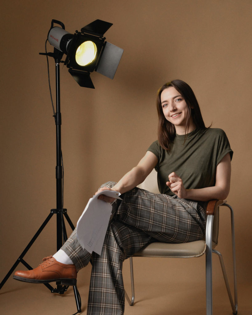 A female screenwriter sat on a chair with a script demonstrating how to pitch a movie | FILMD