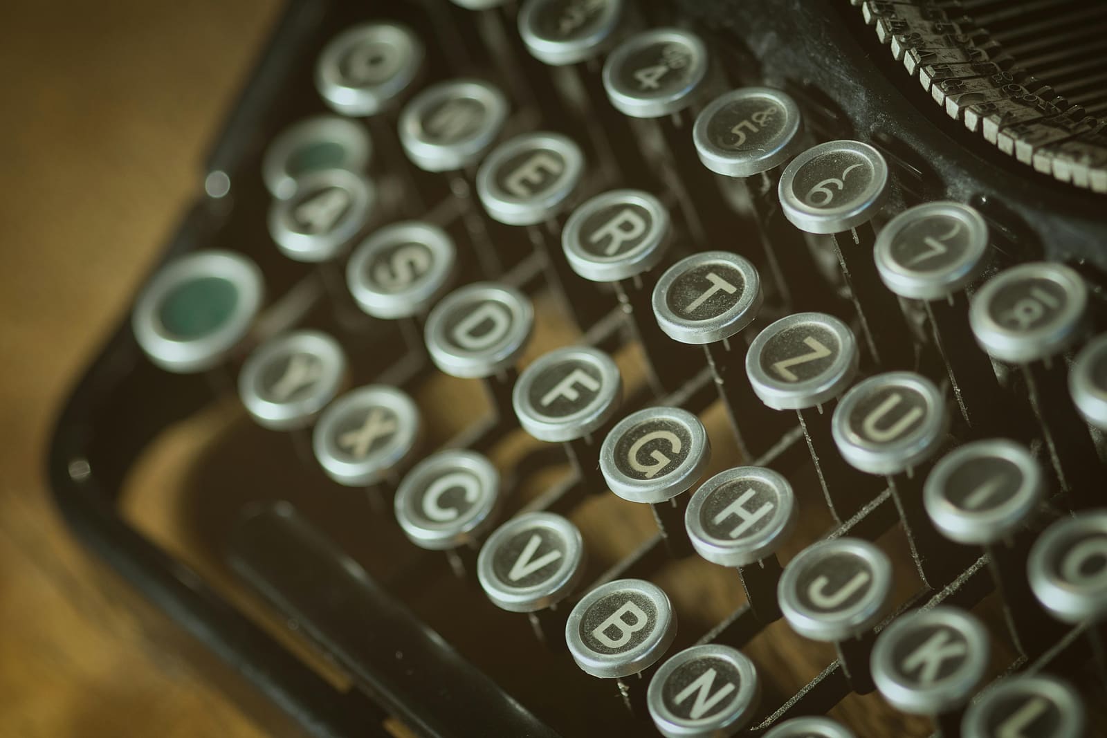 A vintage typewriter on a wooden desk with a blank sheet of paper ready for a script